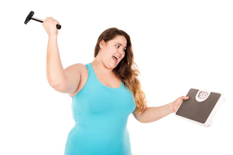 plus size woman showing self-love by smashing a scale