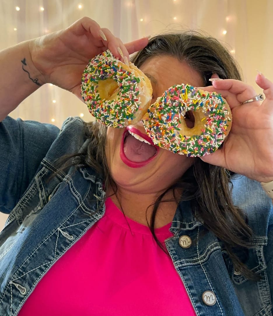 white woman using donuts to make eyes with a big smile